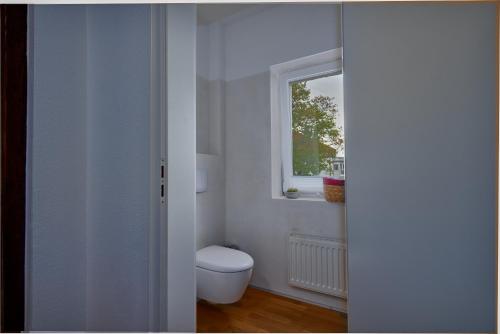 a white bathroom with a toilet and a window at Soesthaus in Soest