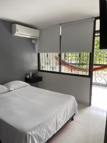 ein Schlafzimmer mit einem weißen Bett und einem großen Fenster in der Unterkunft Apartamento moderno cerca al aeropuerto in Neiva