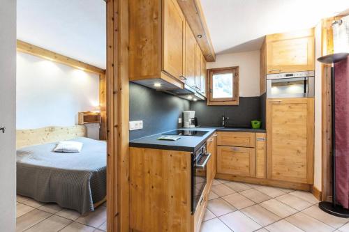 - une cuisine avec un lit dans une chambre avec des placards en bois dans l'établissement Résidence Alpages D - ALPAGES D002 MAE-6331, à Les Allues