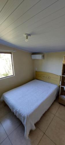 a bedroom with a bed in a room with a window at Suíte o Pescador, praia do rosa in Garopaba