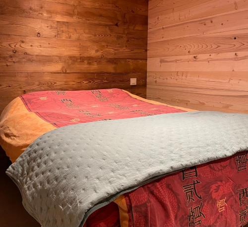 a bed in a room with a wooden wall at Appart 8 pers ac Jacuzzi portes du soleil La Chapelle-Chatel in La Chapelle-dʼAbondance