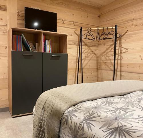 a bedroom with a bed and a book shelf with a television at Appart 8 pers ac Jacuzzi portes du soleil La Chapelle-Chatel in La Chapelle-dʼAbondance