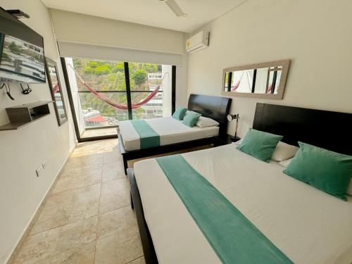 a bedroom with two beds and a large window at Apartasuites VITA 945 RODADERO - By Bedviajes in Santa Marta