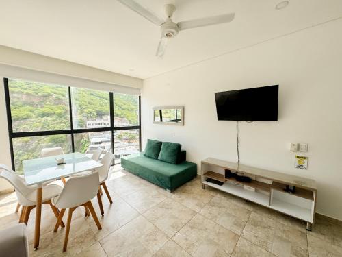 a living room with a green couch and a tv at Apartasuites VITA 945 RODADERO - By Bedviajes in Santa Marta
