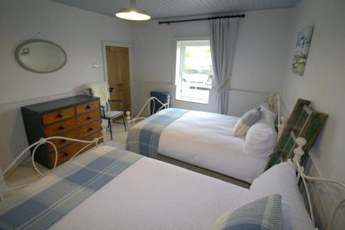 a bedroom with two beds and a dresser and a window at The Oyster House in Dungloe
