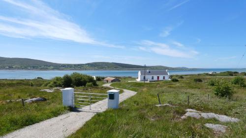 a small white house on a hill with a body of water at The Oyster House in Dungloe