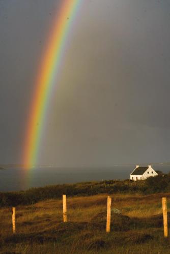 a rainbow in the sky over a field with a house at The Oyster House in Dungloe