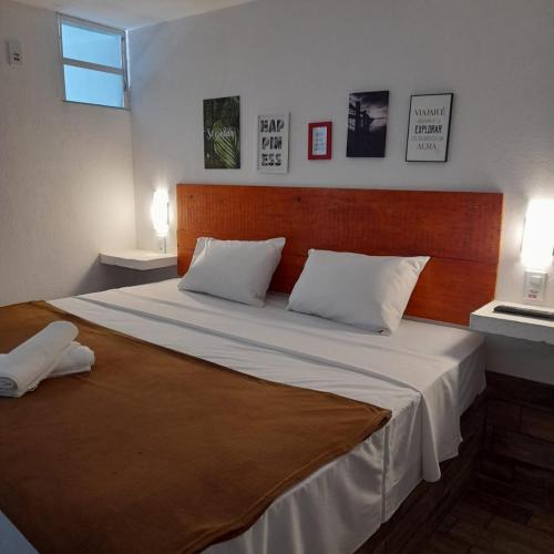 a bedroom with a large bed with a wooden headboard at Pousada Tarkna in Teresópolis
