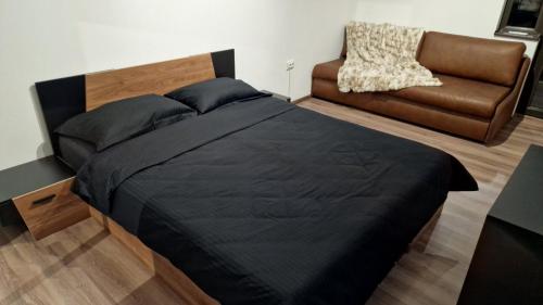 a bedroom with a black bed and a couch at Rebeka Luxury Apartment in Tryavna