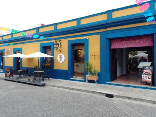 a blue and yellow building with tables and umbrellas at Hotel Casa Margarita in San Cristóbal de Las Casas