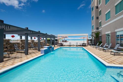 a swimming pool at a hotel with chairs and a building at Residence Inn by Marriott Corpus Christi South in Corpus Christi