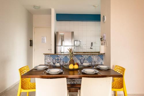 a dining room with a table with chairs and a kitchen at Helbor Atlantis by Doce Lar de Bertioga in Bertioga