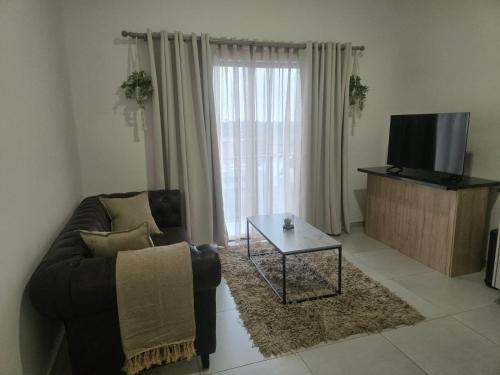 Una sala de estar con un sofá, un televisor y una mesa. en 204 The Base Apartment, en Johannesburgo