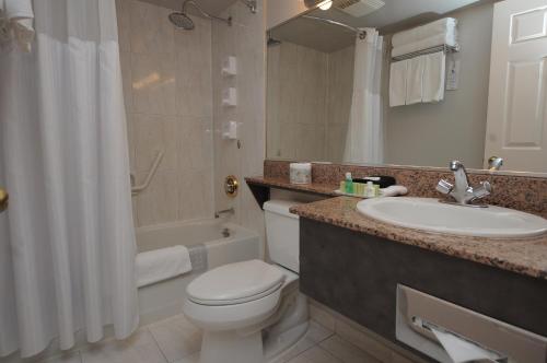 a bathroom with a toilet and a sink and a tub at Rosedale on Robson Suite Hotel in Vancouver