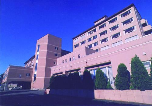 a large building with trees in front of it at Hotel Tetora Resort Tsuruoka in Tsuruoka