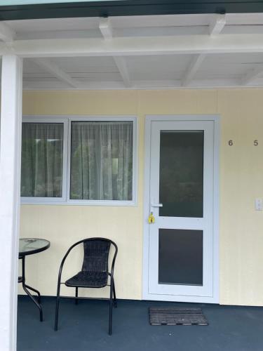 a chair and a table in front of a door at Mataki Motel in Murchison