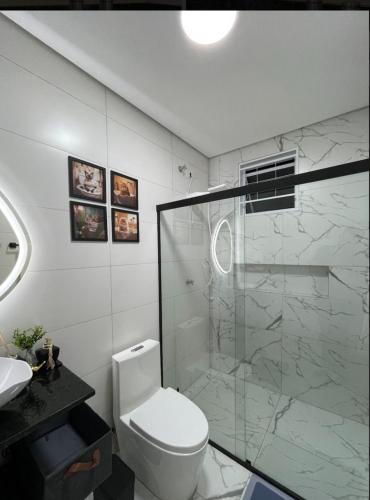 a bathroom with a toilet and a glass shower at Apto no centro de Maringa com garagem in Maringá