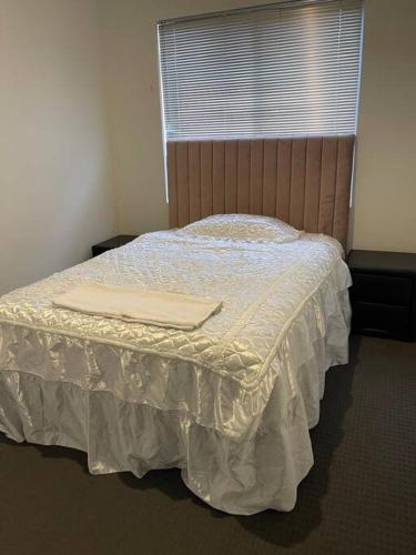 a bedroom with a bed with a white bedspread and a window at Elshaadai Homes in The Vines