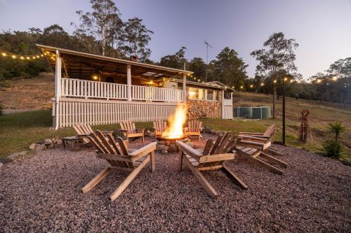 a group of chairs and a fire pit in front of a house at Bellbird Rise Off-Grid Cottage in Conondale