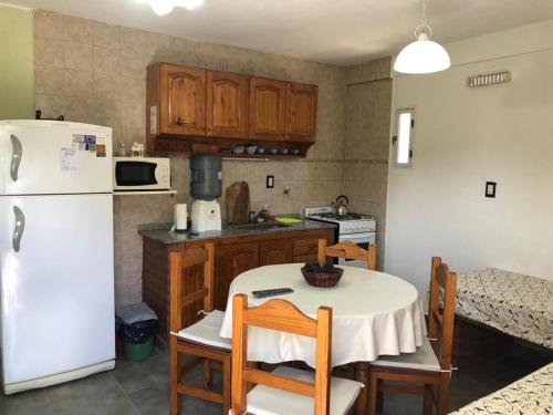 a kitchen with a table and a white refrigerator at Casa Dúplex Nueva Atlantis - Complejo San Norberto in Mar de Ajó