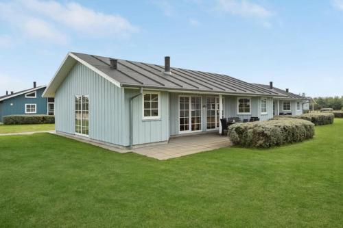a small blue house with a large yard at Dejligt spahus i Seawest in Nørre Nebel