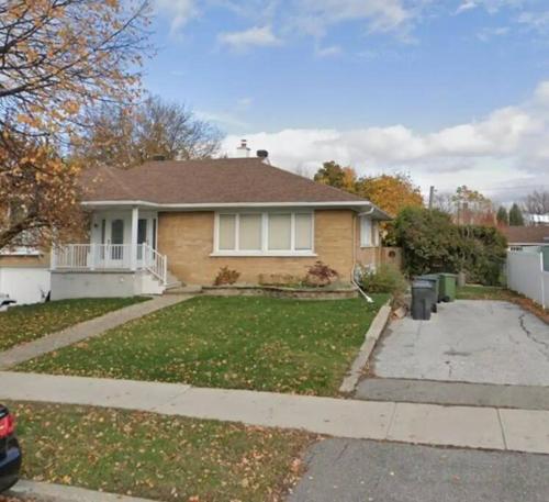 a house with a yard with a driveway at Appartment with Hot Tub and Backyard and Free Parking in Saint-Hyacinthe