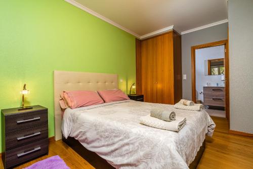 a bedroom with a large bed with a green wall at Green Doors - AC and free parking in Machico