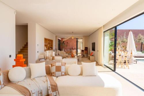 a living room with white furniture and a large window at Dar Al Jenna - Villa de luxe avec piscine privée in Marrakech