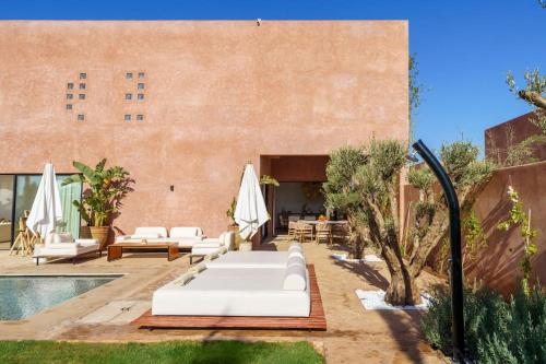 a patio with white furniture and a pool at Dar Al Jenna - Villa de luxe avec piscine privée in Marrakech