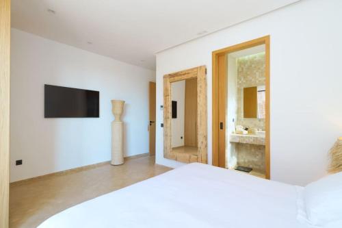 a white room with a television and a mirror at Dar Al Jenna - Villa de luxe avec piscine privée in Marrakech