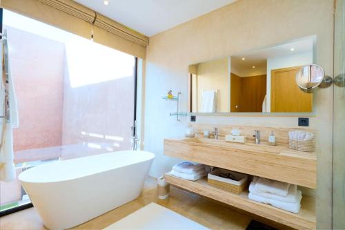 a bathroom with a tub and a large mirror at Dar Al Jenna - Villa de luxe avec piscine privée in Marrakech