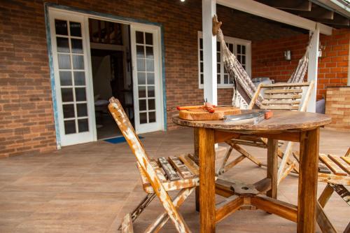 a wooden table and two chairs on a patio at Apartamentos exclusivos e equipado com varanda ou terraço com Pôr do sol, cozinha privativa, Wi-Fi 600MBs, a 700m da praia de Itapirubá e 1km da BR-101 in Imbituba