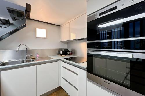 une cuisine avec des armoires blanches et un four noir dans l'établissement Charming atypical apartment - Gare de l'Est, à Paris