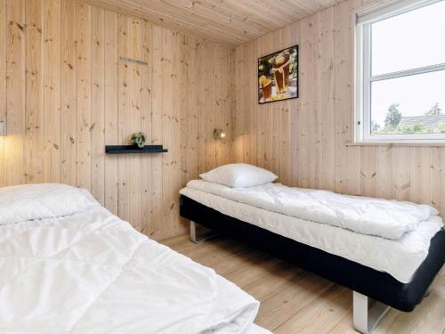 two beds in a room with wooden walls and a window at 5 star holiday home in Idestrup in Marielyst