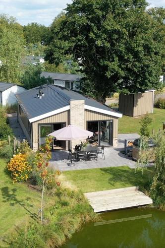 a house with a table and an umbrella in the yard at Wellness Chalet Veluwemeer in Biddinghuizen