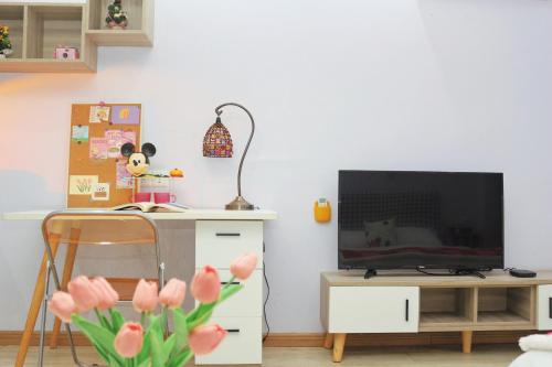ein Wohnzimmer mit Fernseher und Schreibtisch mit rosa Blumen in der Unterkunft suansuan Apartment in Chengdu