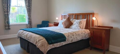 a bedroom with a bed with a blue blanket on it at Murrells Grand View House in Manapouri