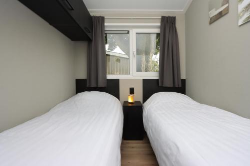two beds in a bedroom with a window at Wellness Chalet Veluwemeer in Biddinghuizen