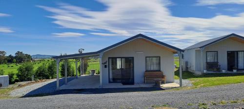 a small house with a porch in a field at Meander Country Cabins in Meander