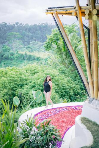 a woman in a black dress standing on a pile of flowers at Danaswari Bali Bamboo House in Selat