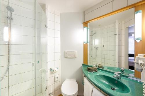 a bathroom with a green sink and a toilet at Hotel Ibis Bregenz in Bregenz