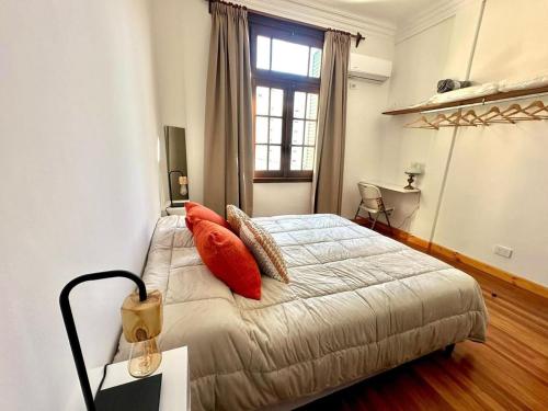 a bedroom with a bed with orange pillows and a window at 120 años de historia a 1 cuadra del Obelisco in Buenos Aires