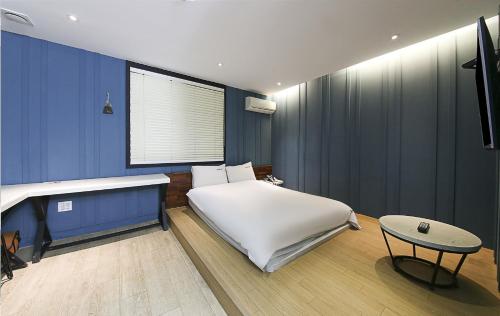 a bedroom with a white bed and a table at Ignis Hotel busan sports complex branch in Busan