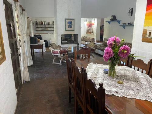 a dining room and living room with a table with pink flowers at El encuentro in Unquillo