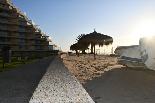 a beach with some straw umbrellas and a building at San Alfonso del Mar Ideal in Mirasol
