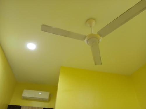 a ceiling fan in a room with a yellow wall at Hill View Paka Homestay in Paka