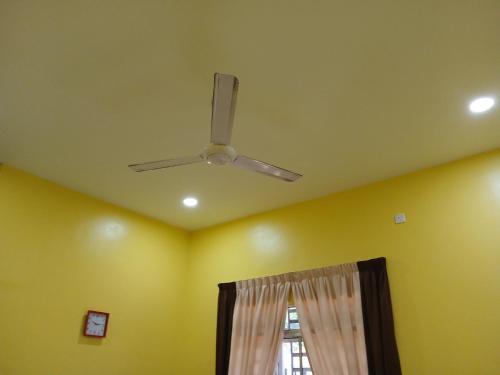 a ceiling fan in a room with a window at Hill View Paka Homestay in Paka