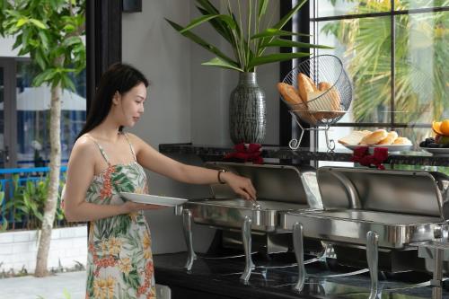 a woman in a dress preparing food in a kitchen at Serene Nature Hotel & Spa in Hoi An