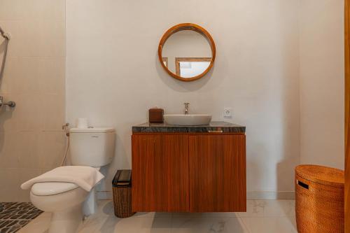 a bathroom with a sink and a toilet and a mirror at Sakya Villa Canggu By Bali Cabin in Canggu