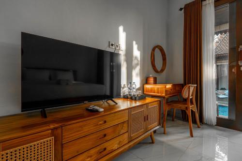 a living room with a large television on a wooden entertainment center at Sakya Villa Canggu By Bali Cabin in Canggu